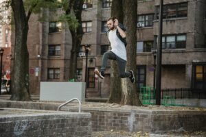 Side view of young bearded man in casual outfit doing parkour in city park